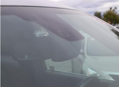 close up photo of a Nissan windshield with a rain sensor